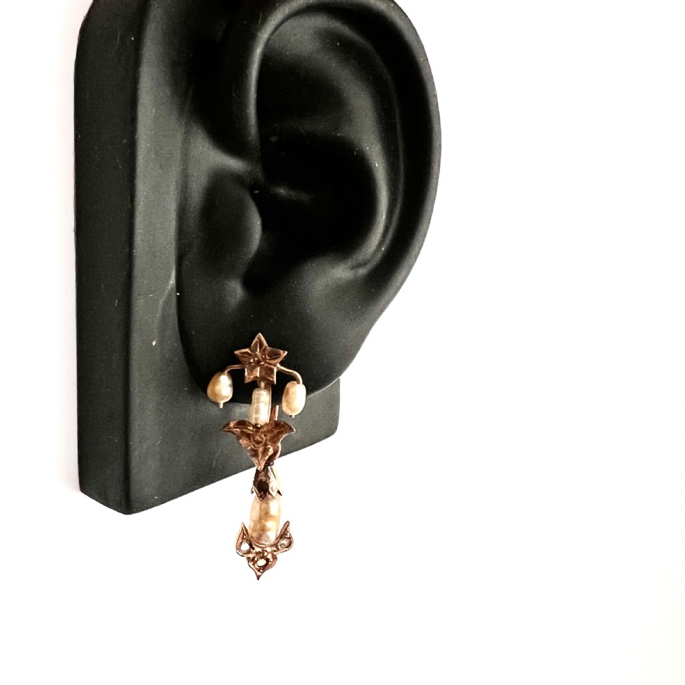 A pair of Art Nouveau gold drop earrings featuring star tops, leaf motifs set with small diamonds, and suspended baroque pearls. View IV