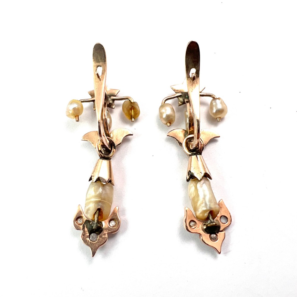 A pair of Art Nouveau gold drop earrings featuring star tops, leaf motifs set with small diamonds, and suspended baroque pearls. View VI