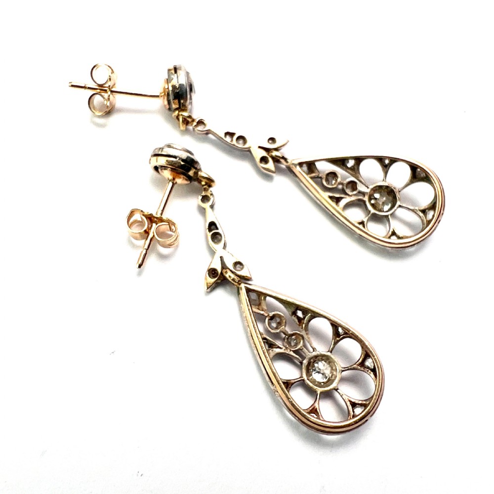 A pair of antique silver-topped gold drop earrings featuring openwork teardrop pendants set with old-cut diamonds, resting inside a blue fitted box. View III