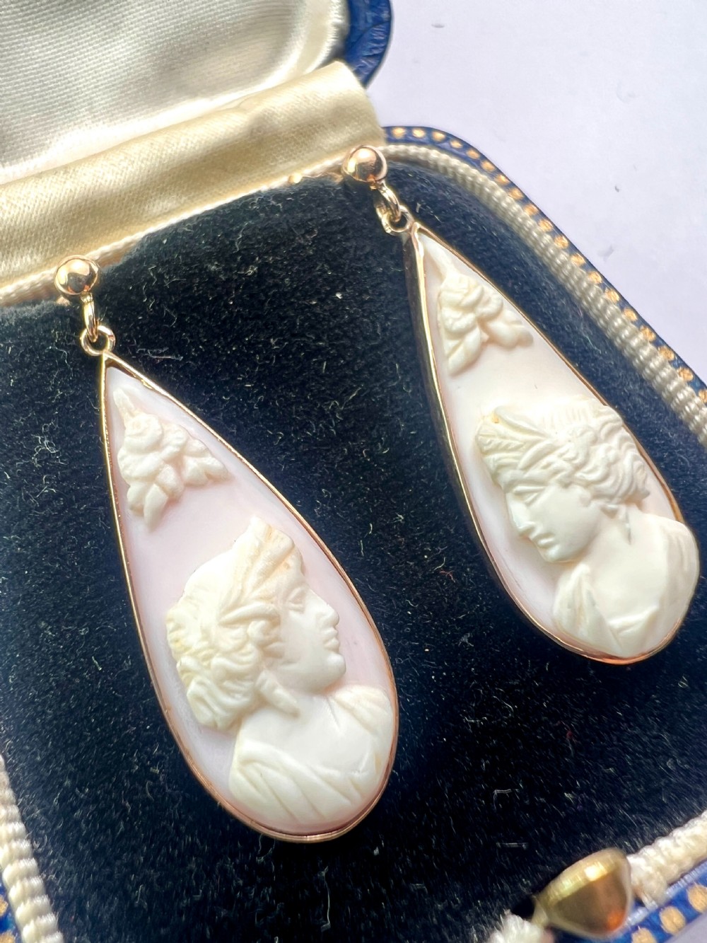 A pair of teardrop-shaped 9ct gold drop earrings featuring carved shell cameos with classical profile portraits set against a pink shell background. View VII
