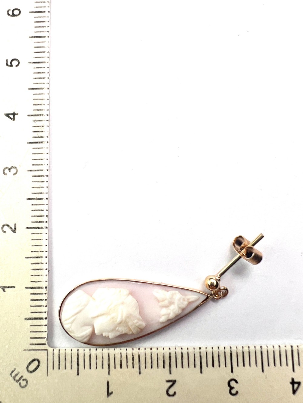 A pair of teardrop-shaped 9ct gold drop earrings featuring carved shell cameos with classical profile portraits set against a pink shell background. View VIII