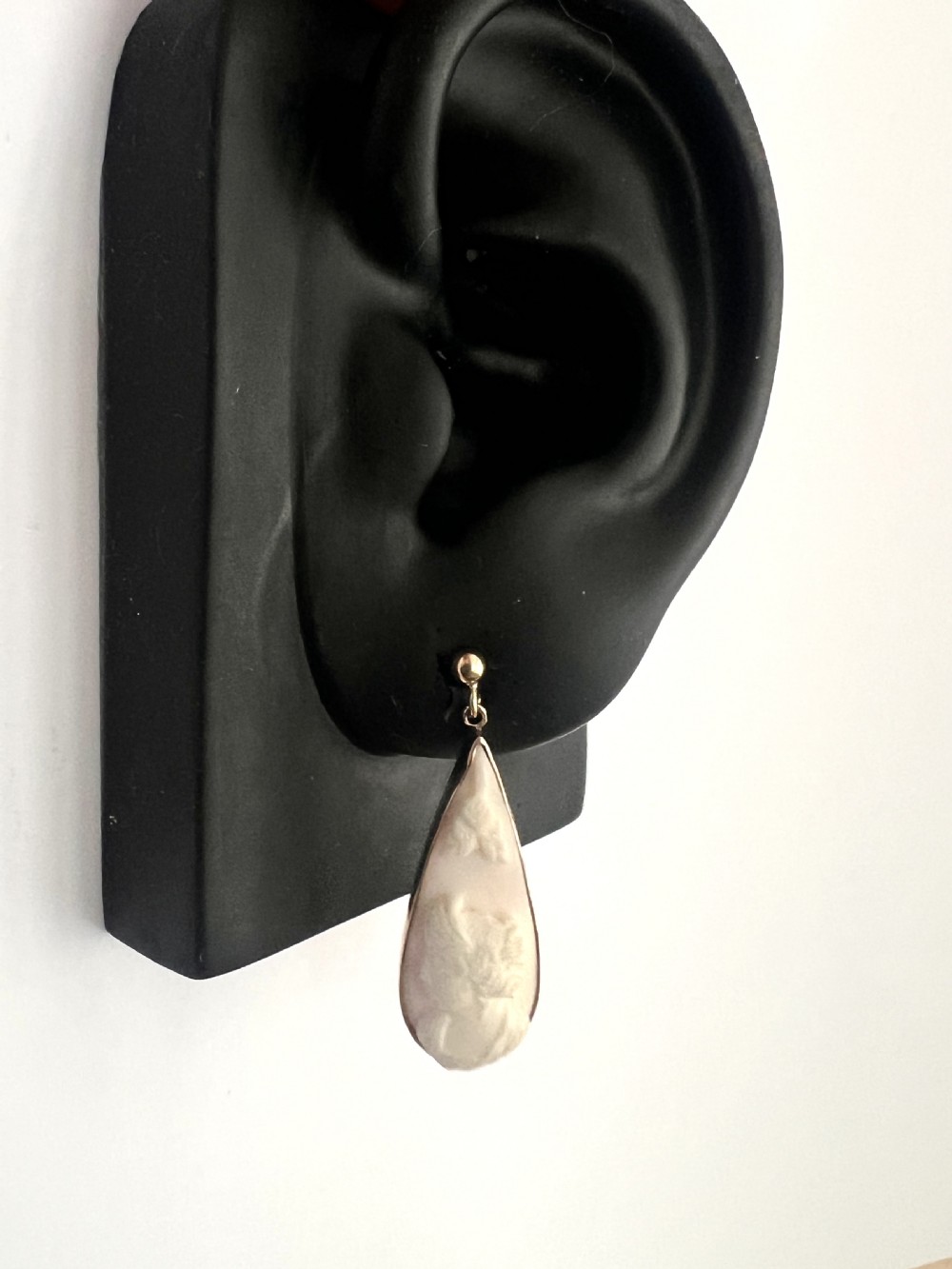 A pair of teardrop-shaped 9ct gold drop earrings featuring carved shell cameos with classical profile portraits set against a pink shell background. View X