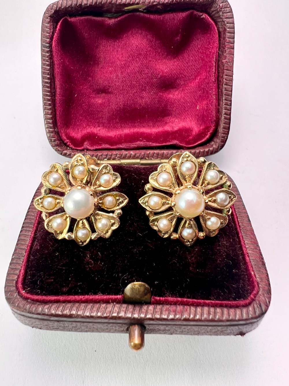 A pair of Victorian 9ct gold earrings featuring a central pearl surrounded by eight smaller seed pearls arranged in a floral cluster pattern.