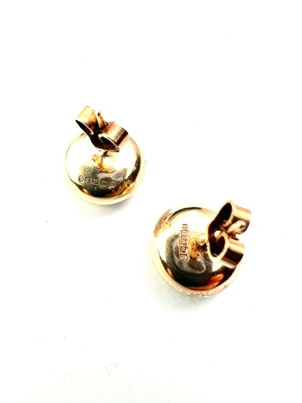 A pair of circular domed yellow gold stud earrings featuring hand-engraved scrollwork across the surface. View II