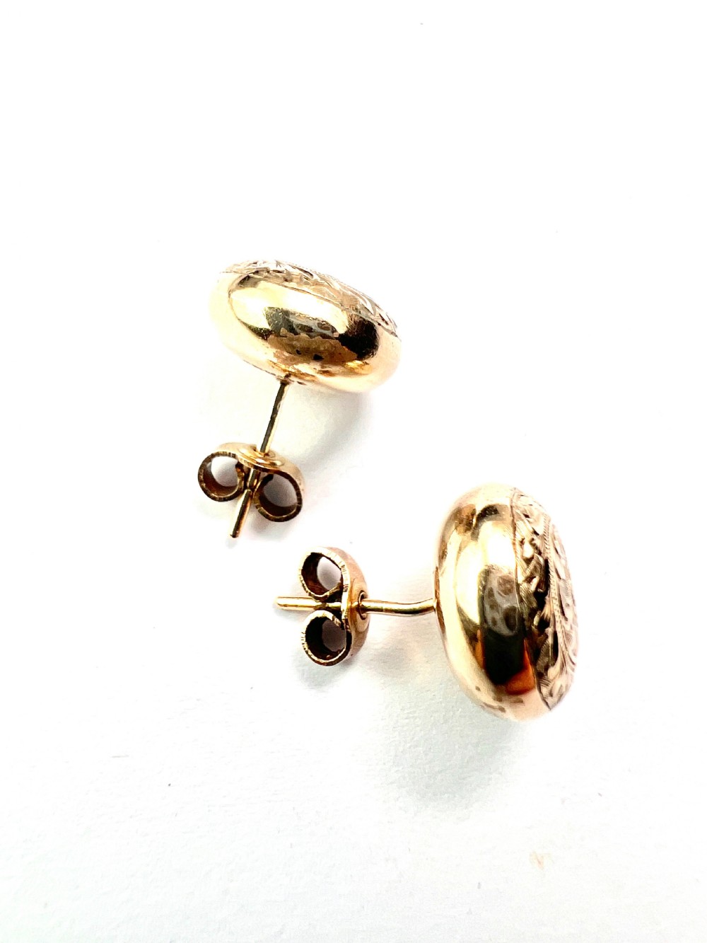 A pair of circular domed yellow gold stud earrings featuring hand-engraved scrollwork across the surface. View III