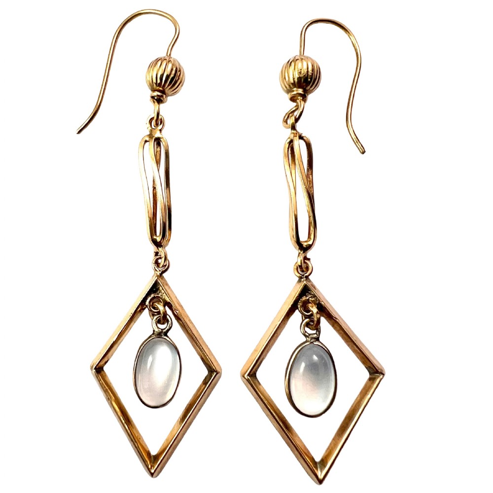 A pair of yellow gold drop earrings featuring ribbed shepherd hooks, linear twisted wire links, and open diamond-shaped frames containing oval moonstone cabochons.