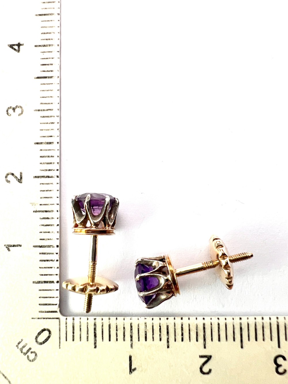 Pair of antique stud earrings featuring circular purple amethysts in multi-prong silver crown settings with yellow gold posts and scalloped backings. View VII