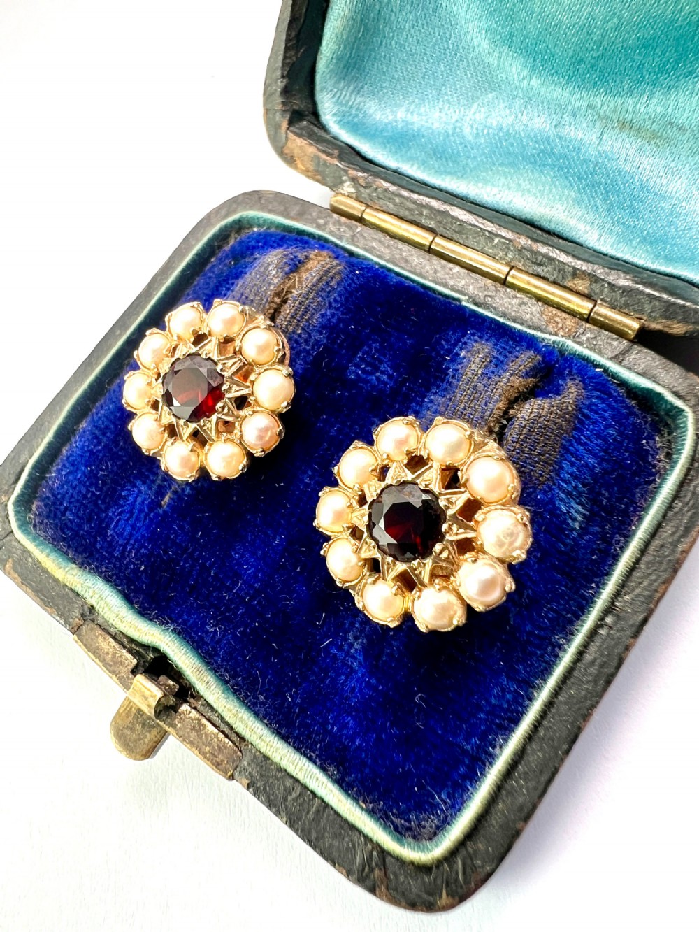 A pair of Victorian gold cluster earrings featuring a central round faceted red garnet surrounded by seed pearls set in a starburst pattern. View II