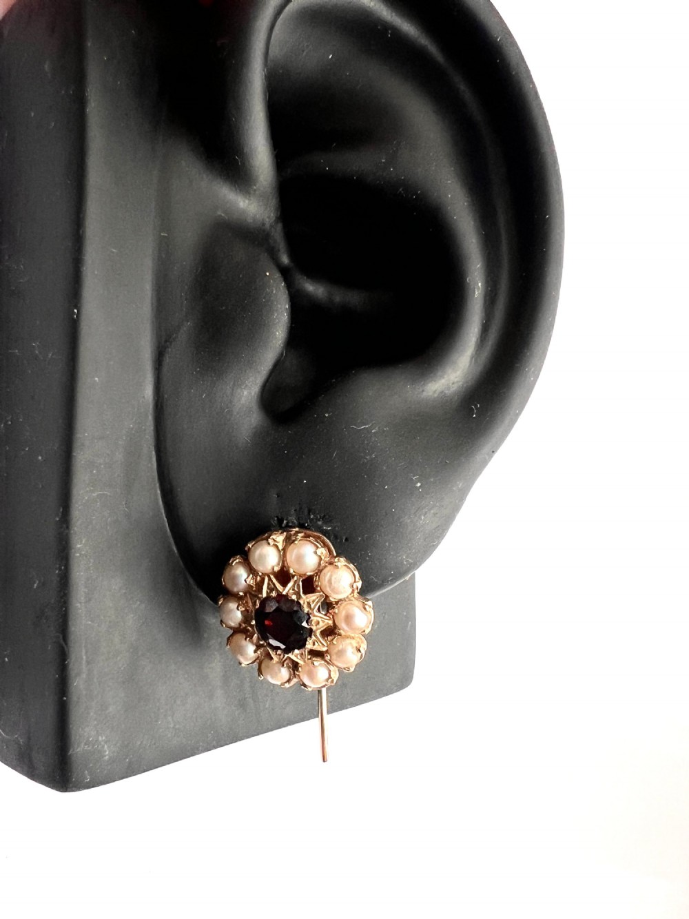 A pair of Victorian gold cluster earrings featuring a central round faceted red garnet surrounded by seed pearls set in a starburst pattern. View VI