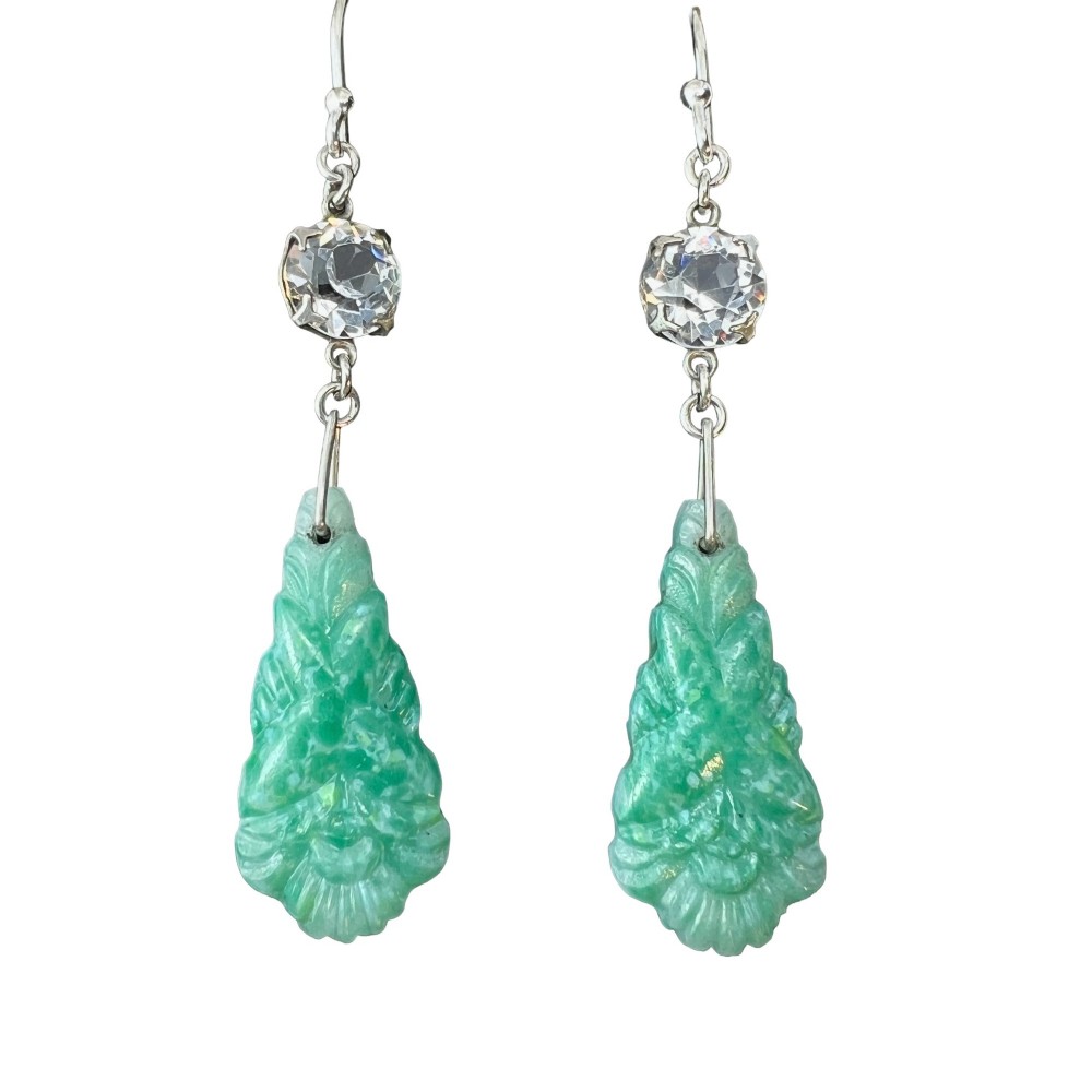 A pair of silver drop earrings featuring clear round crystals above carved green glass teardrop pendants.