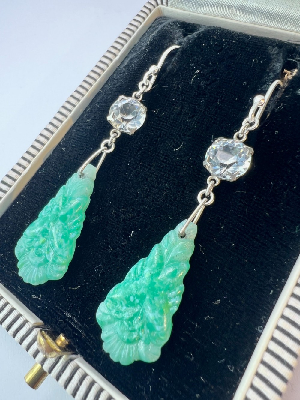 A pair of silver drop earrings featuring clear round crystals above carved green glass teardrop pendants. View III