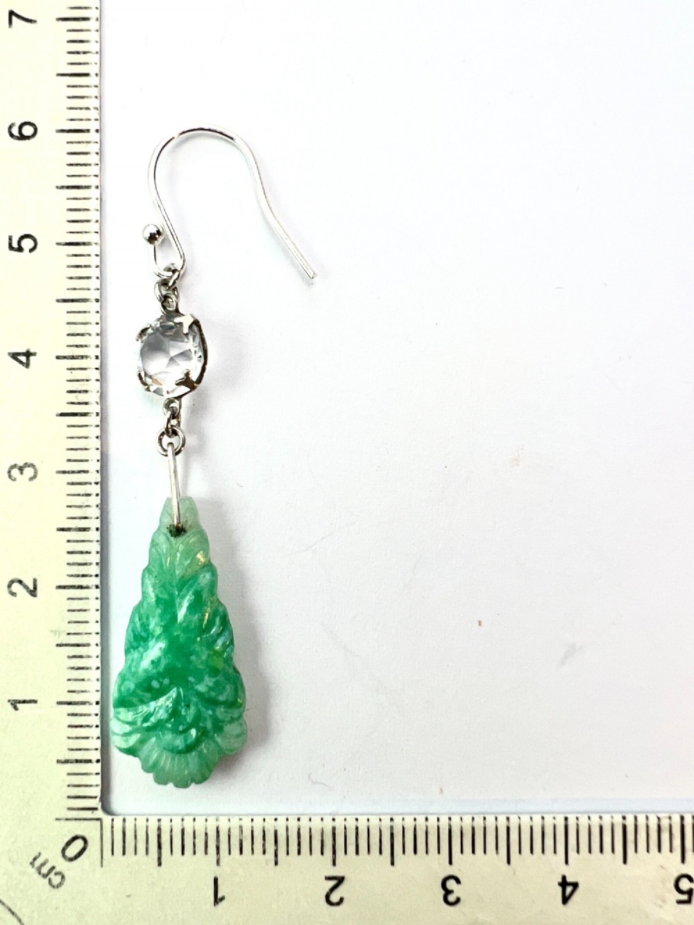 A pair of silver drop earrings featuring clear round crystals above carved green glass teardrop pendants. View VI