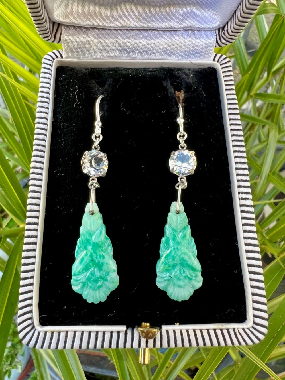 A pair of silver drop earrings featuring clear round crystals above carved green glass teardrop pendants. View VII