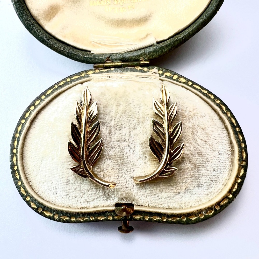 A pair of 9ct yellow gold stud earrings crafted in the shape of curved laurel leaf branches with textured vein details. View II