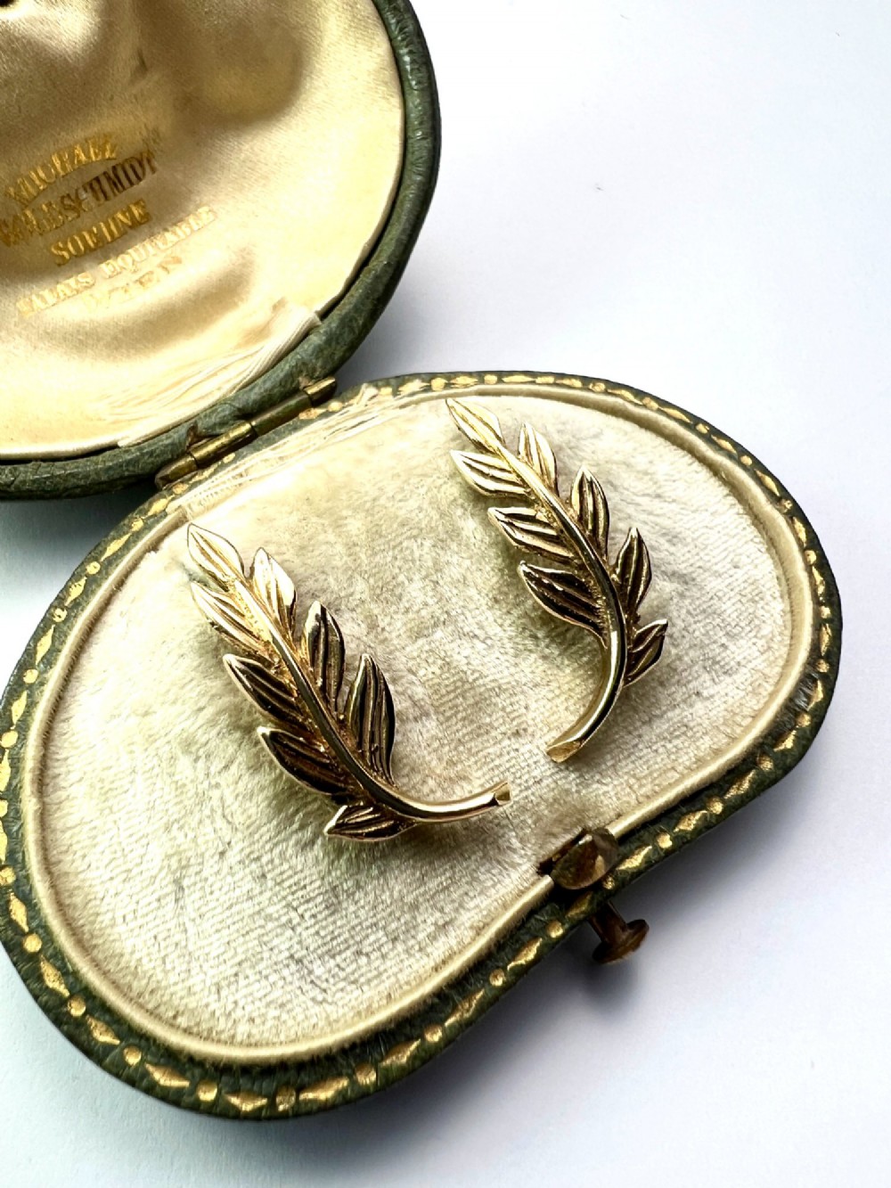 A pair of 9ct yellow gold stud earrings crafted in the shape of curved laurel leaf branches with textured vein details. View III