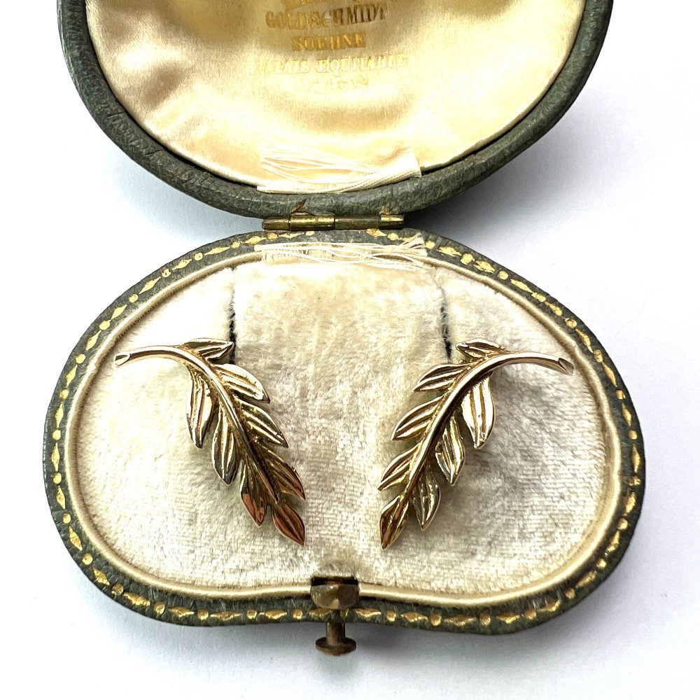 A pair of 9ct yellow gold stud earrings crafted in the shape of curved laurel leaf branches with textured vein details. View IV