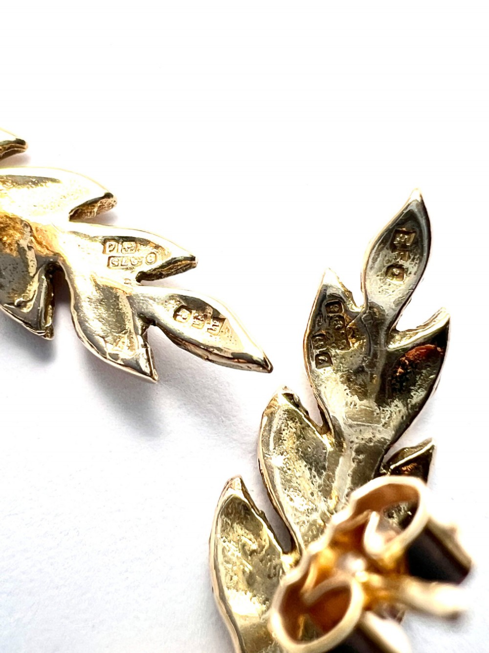 A pair of 9ct yellow gold stud earrings crafted in the shape of curved laurel leaf branches with textured vein details. View V