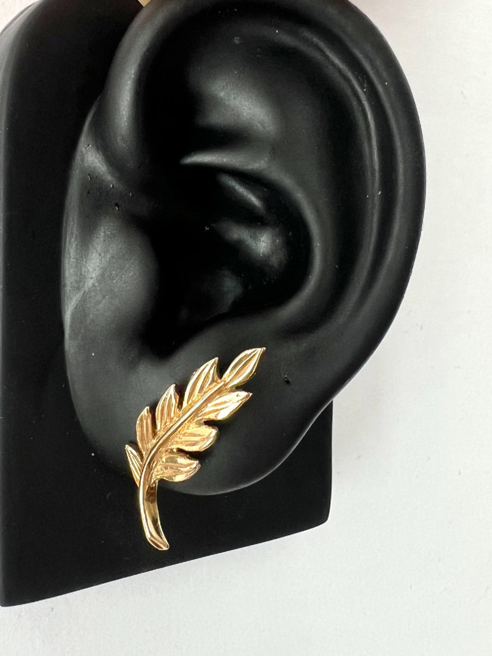A pair of 9ct yellow gold stud earrings crafted in the shape of curved laurel leaf branches with textured vein details. View IX