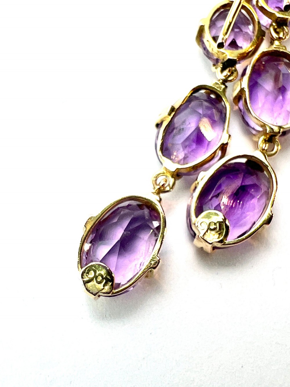 A pair of antique 9ct yellow gold drop earrings, each set with three articulated oval faceted purple amethysts in claw mounts. View IV
