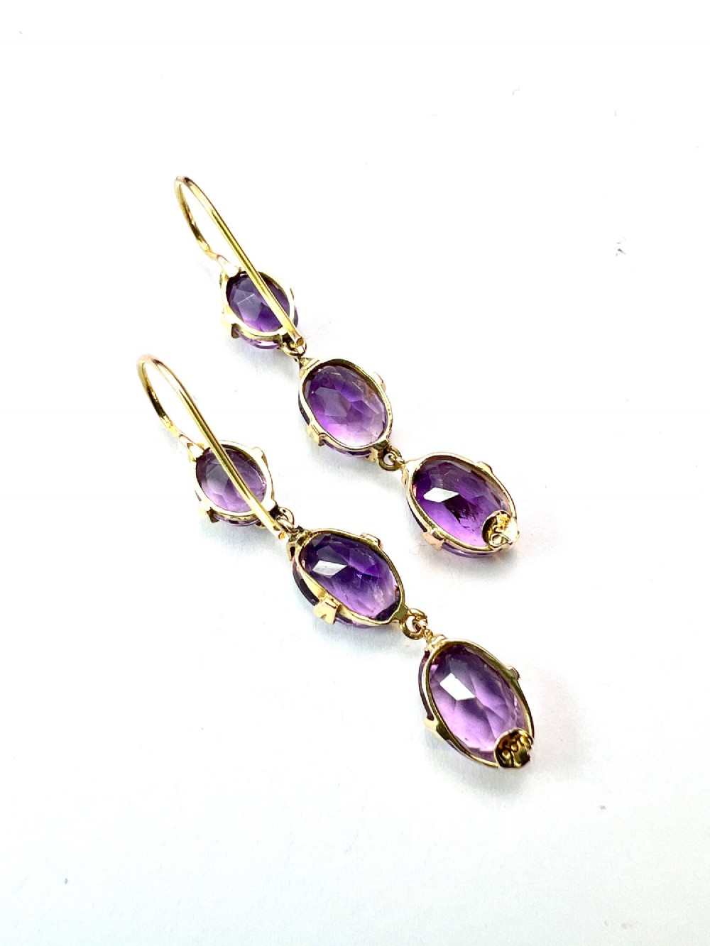 A pair of antique 9ct yellow gold drop earrings, each set with three articulated oval faceted purple amethysts in claw mounts. View V