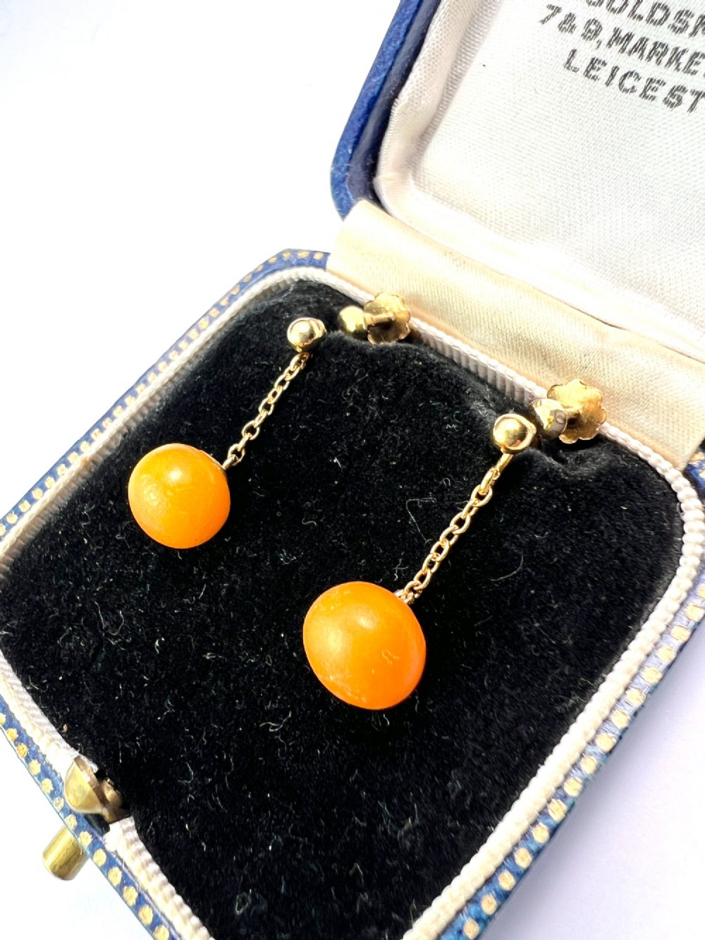 A pair of Edwardian 9ct gold drop earrings featuring spherical amber beads suspended from fine link chains. View II