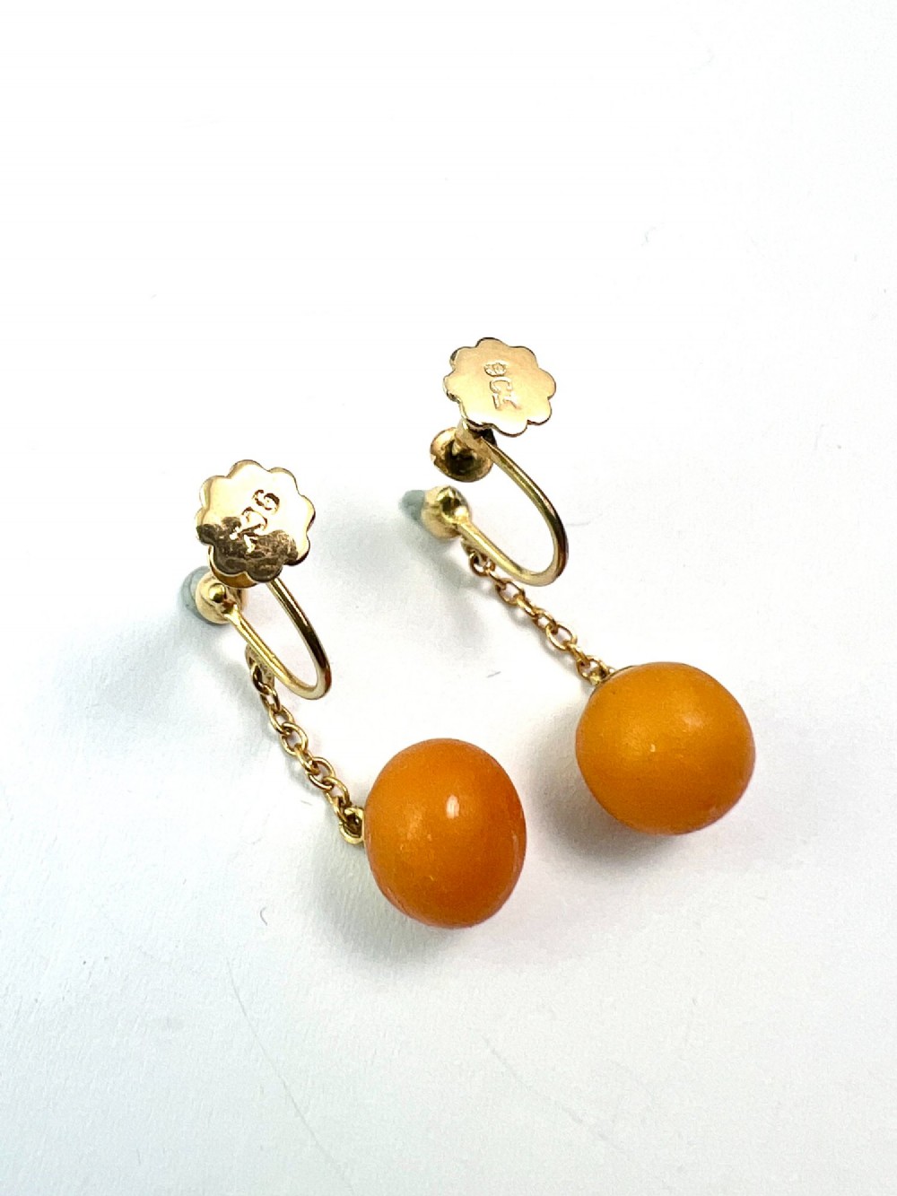 A pair of Edwardian 9ct gold drop earrings featuring spherical amber beads suspended from fine link chains. View IV