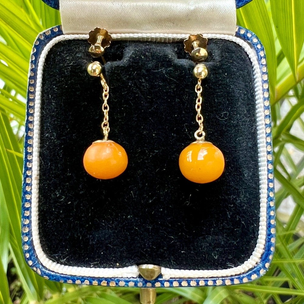 A pair of Edwardian 9ct gold drop earrings featuring spherical amber beads suspended from fine link chains. View VIII