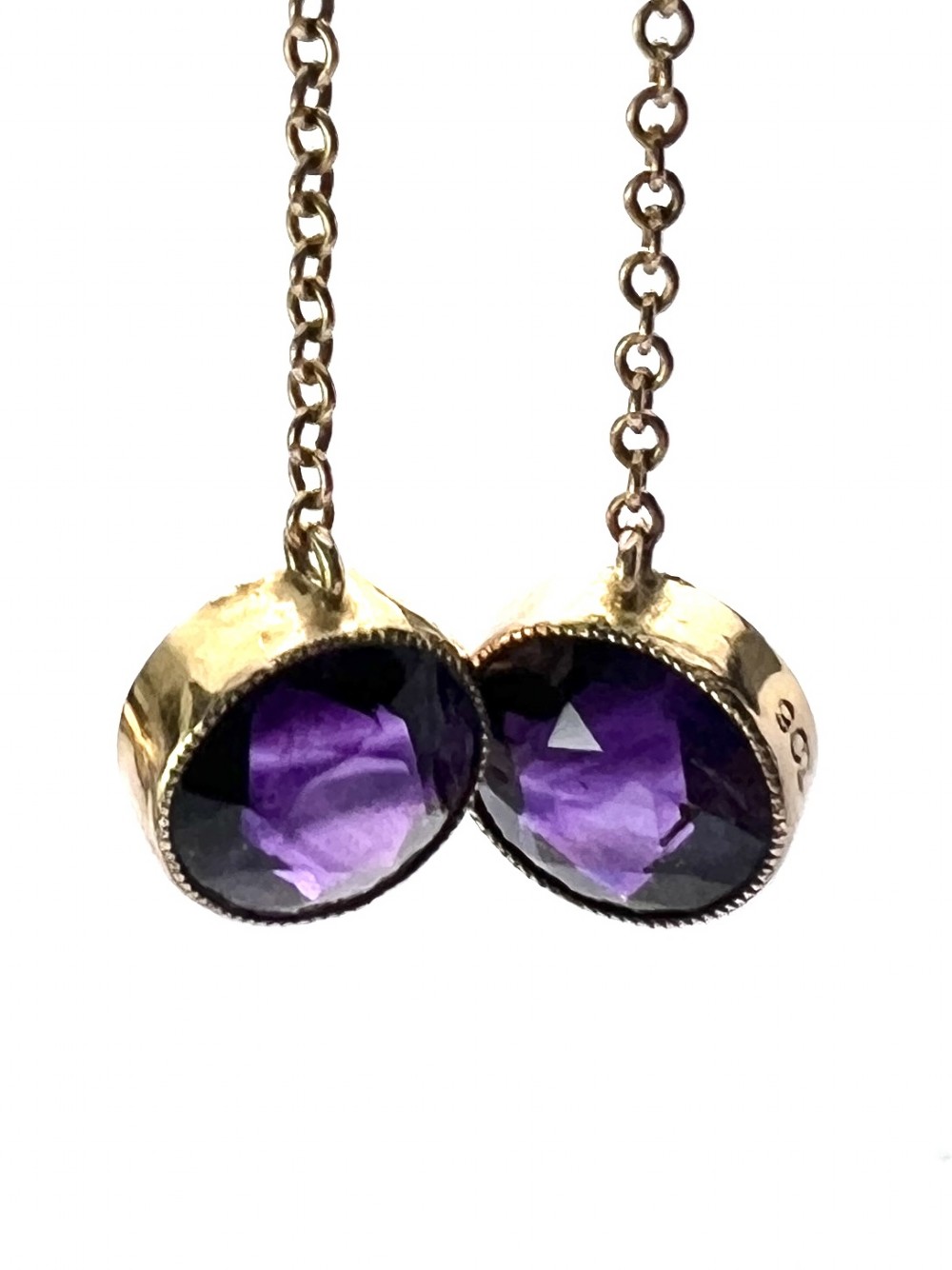 A pair of Edwardian 9ct yellow gold drop earrings featuring round, bezel-set faceted purple amethysts suspended from fine link chains.