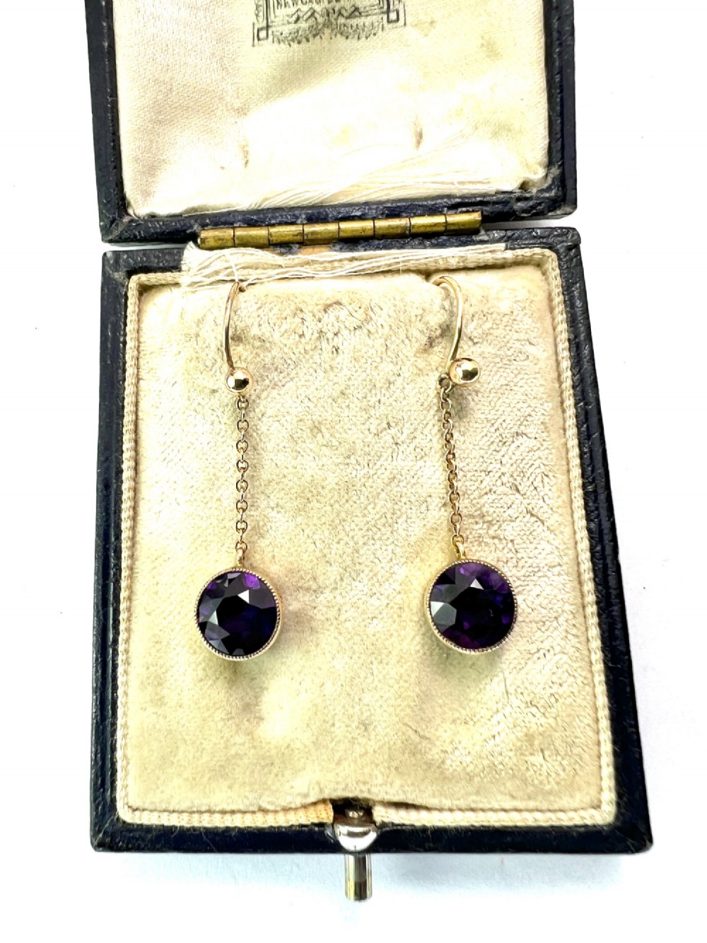 A pair of Edwardian 9ct yellow gold drop earrings featuring round, bezel-set faceted purple amethysts suspended from fine link chains. View II