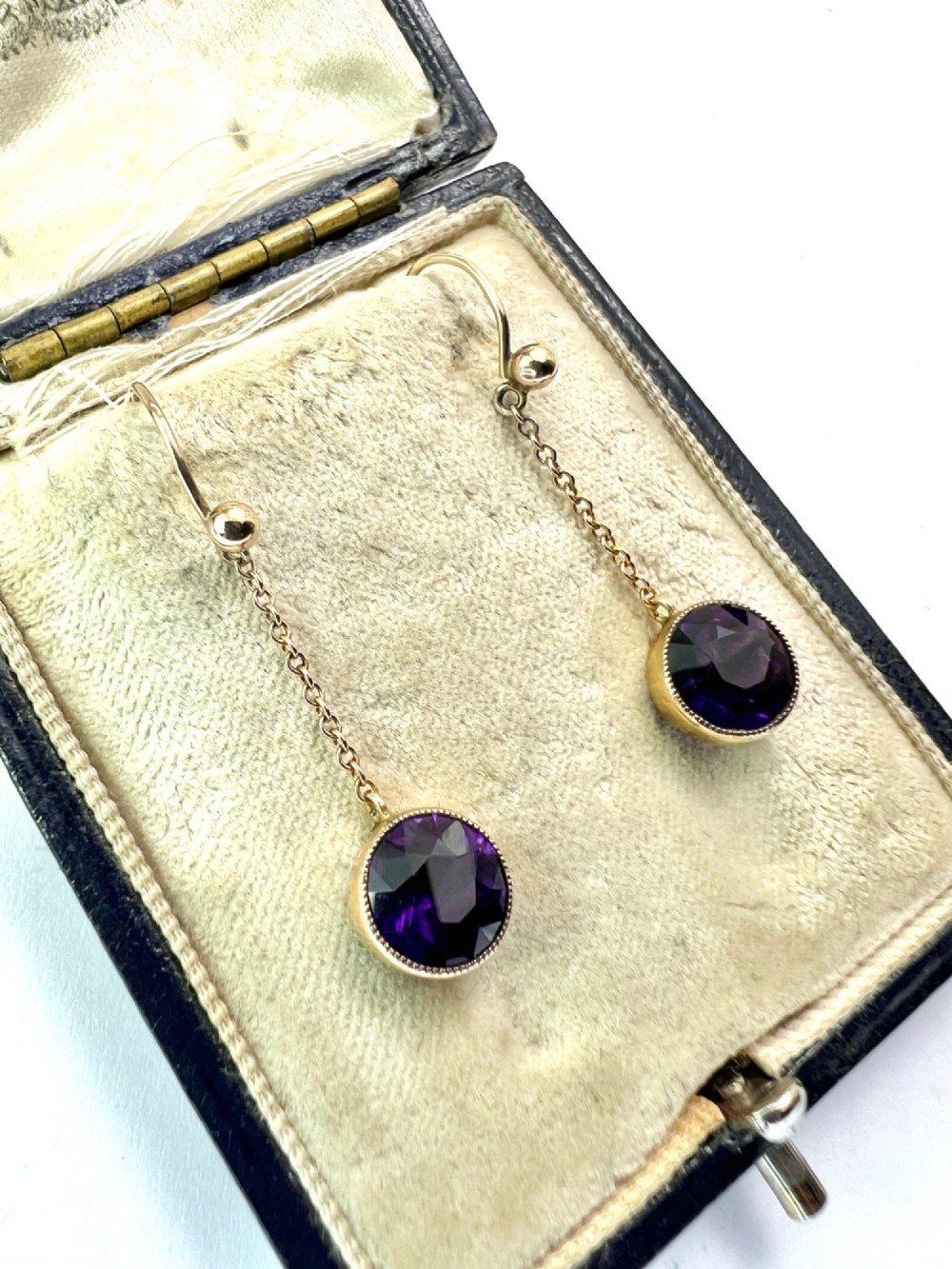 A pair of Edwardian 9ct yellow gold drop earrings featuring round, bezel-set faceted purple amethysts suspended from fine link chains. View IV