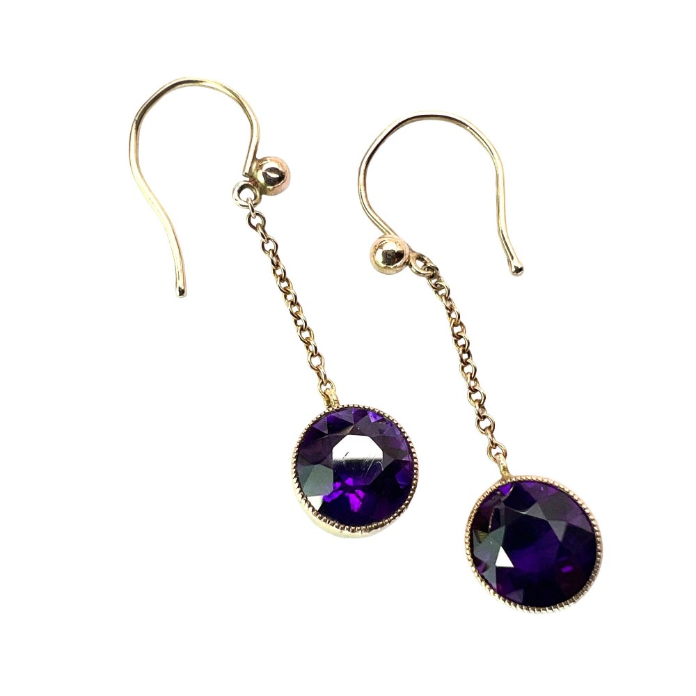 A pair of Edwardian 9ct yellow gold drop earrings featuring round, bezel-set faceted purple amethysts suspended from fine link chains. View V