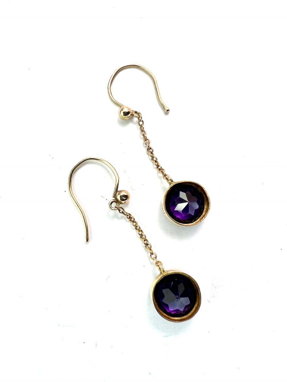 A pair of Edwardian 9ct yellow gold drop earrings featuring round, bezel-set faceted purple amethysts suspended from fine link chains. View VII