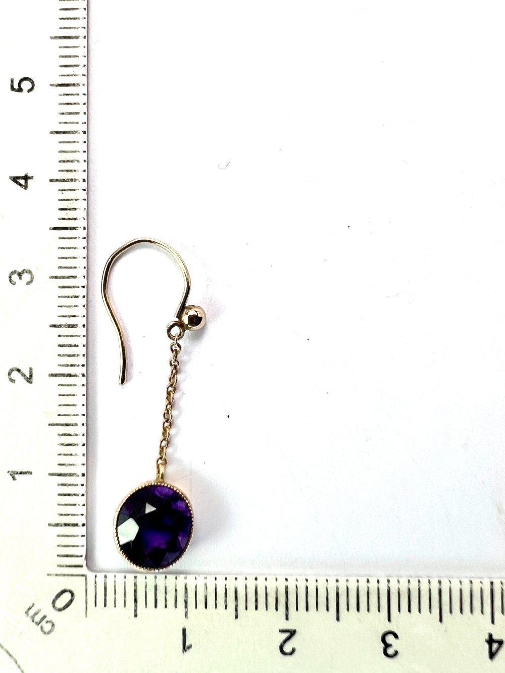 A pair of Edwardian 9ct yellow gold drop earrings featuring round, bezel-set faceted purple amethysts suspended from fine link chains. View VIII