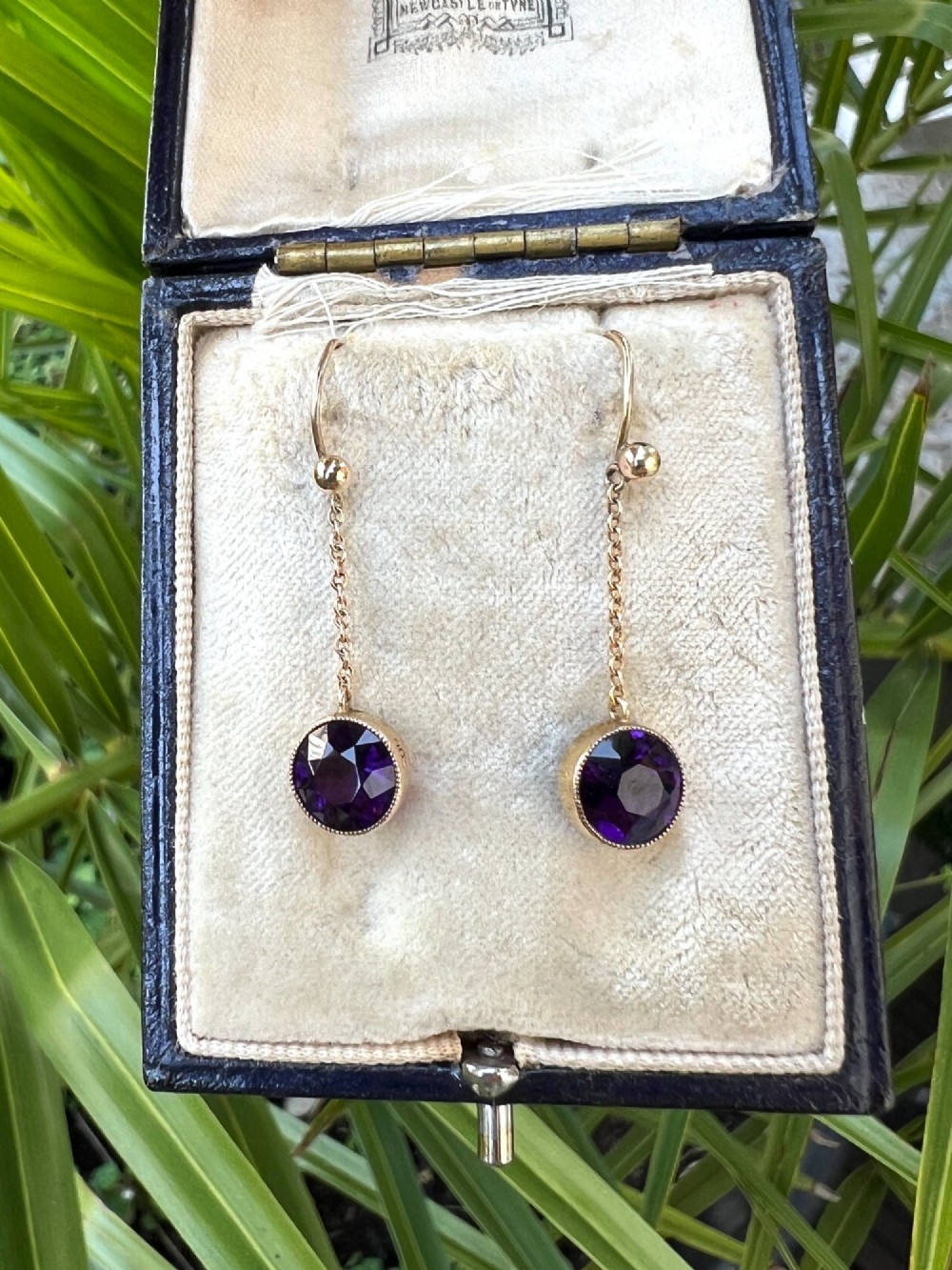 A pair of Edwardian 9ct yellow gold drop earrings featuring round, bezel-set faceted purple amethysts suspended from fine link chains. View IX