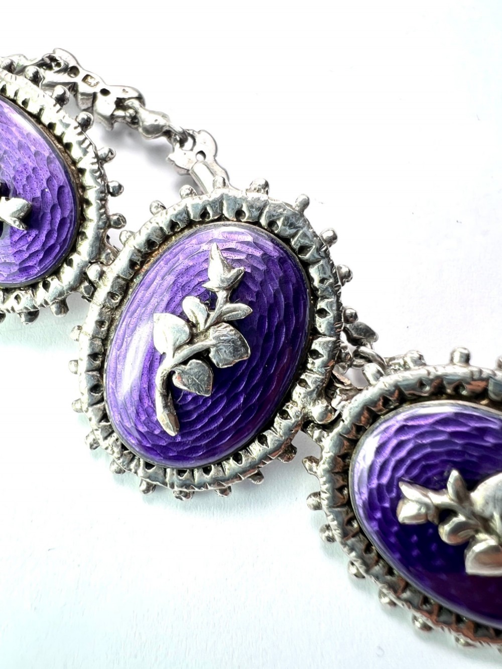 A matching silver jewellery set featuring purple guilloche enamel panels decorated with silver leaf motifs, including drop earrings, a ring, and an articulated link bracelet. View VI