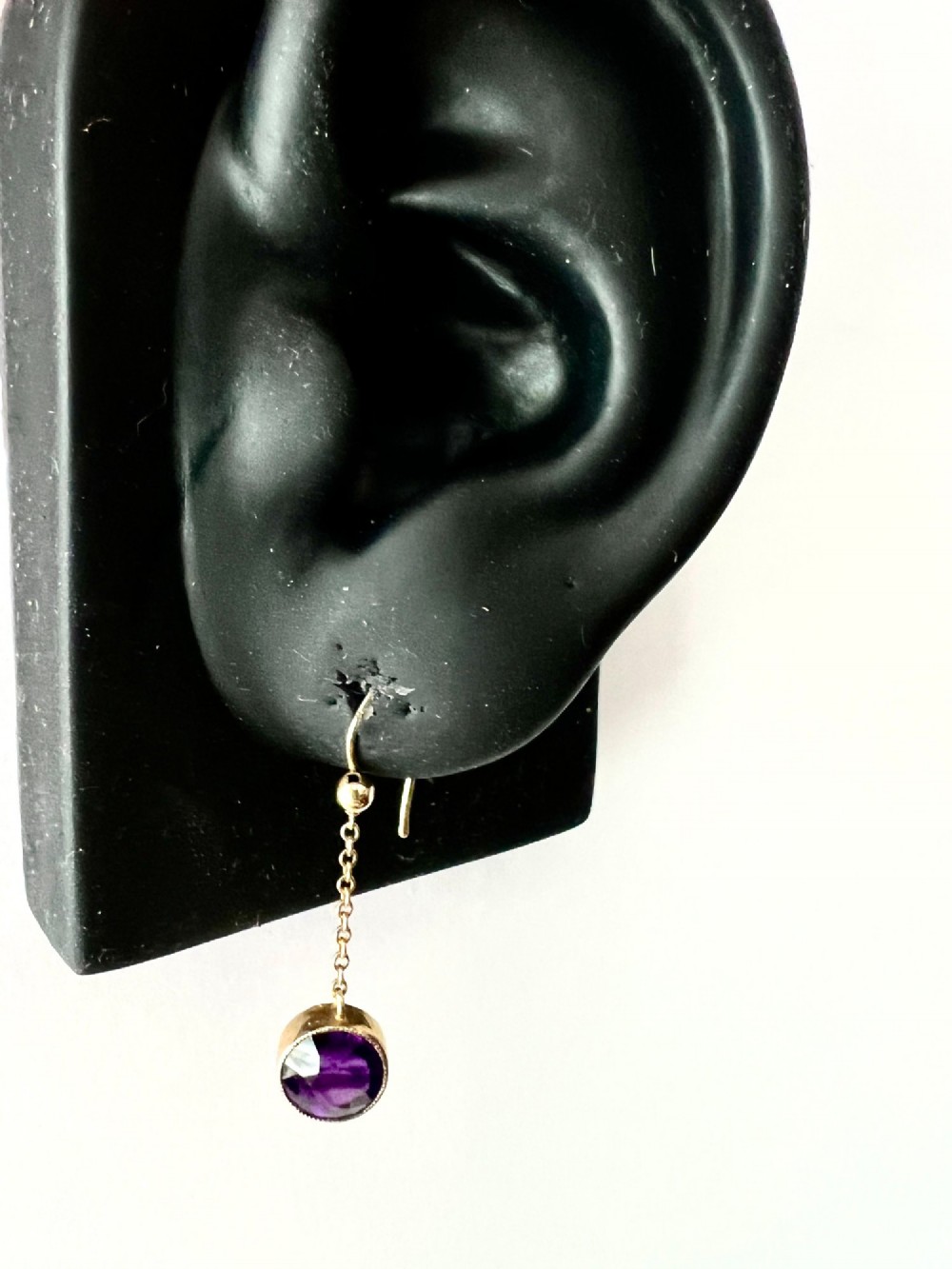A pair of Edwardian 9ct yellow gold drop earrings featuring round, bezel-set faceted purple amethysts suspended from fine link chains. View X