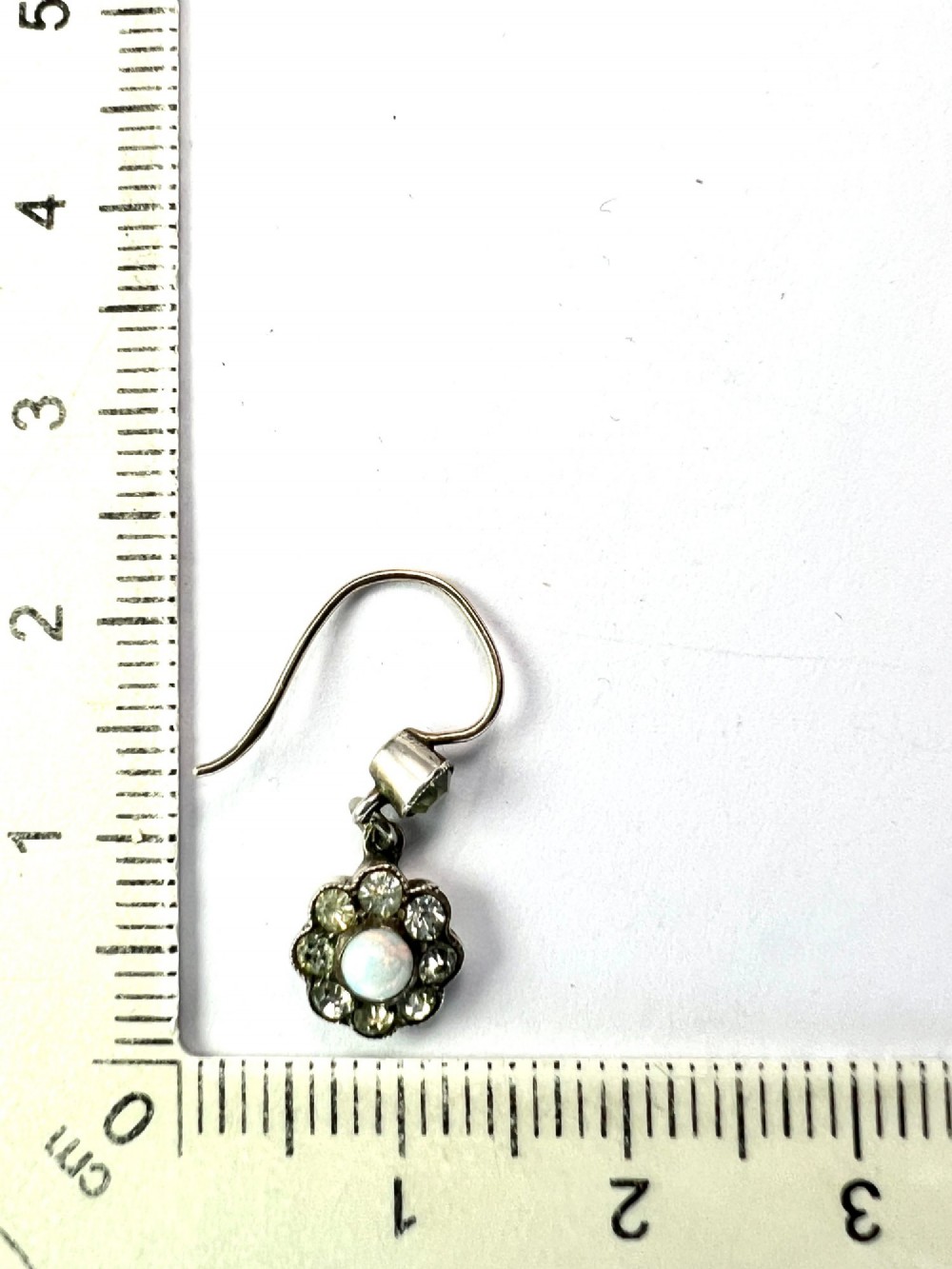 A pair of antique silver drop earrings featuring central opals surrounded by sparkling paste stones in floral cluster settings. View IV