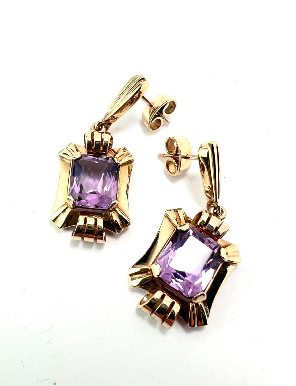 A pair of late Art Deco gold drop earrings featuring rectangular emerald-cut purple amethyst stones set within fluted geometric mounts. View II