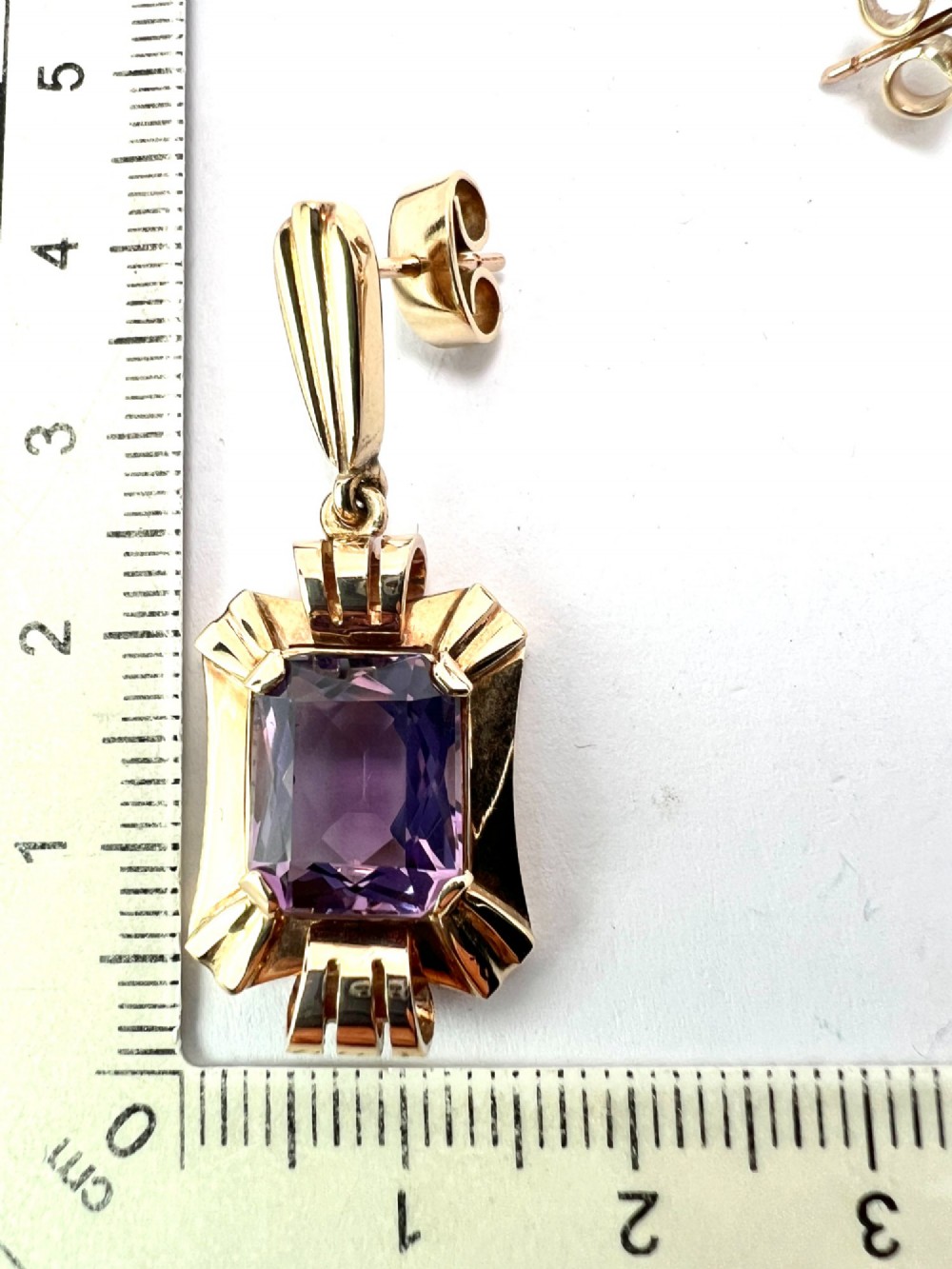 A pair of late Art Deco gold drop earrings featuring rectangular emerald-cut purple amethyst stones set within fluted geometric mounts. View III