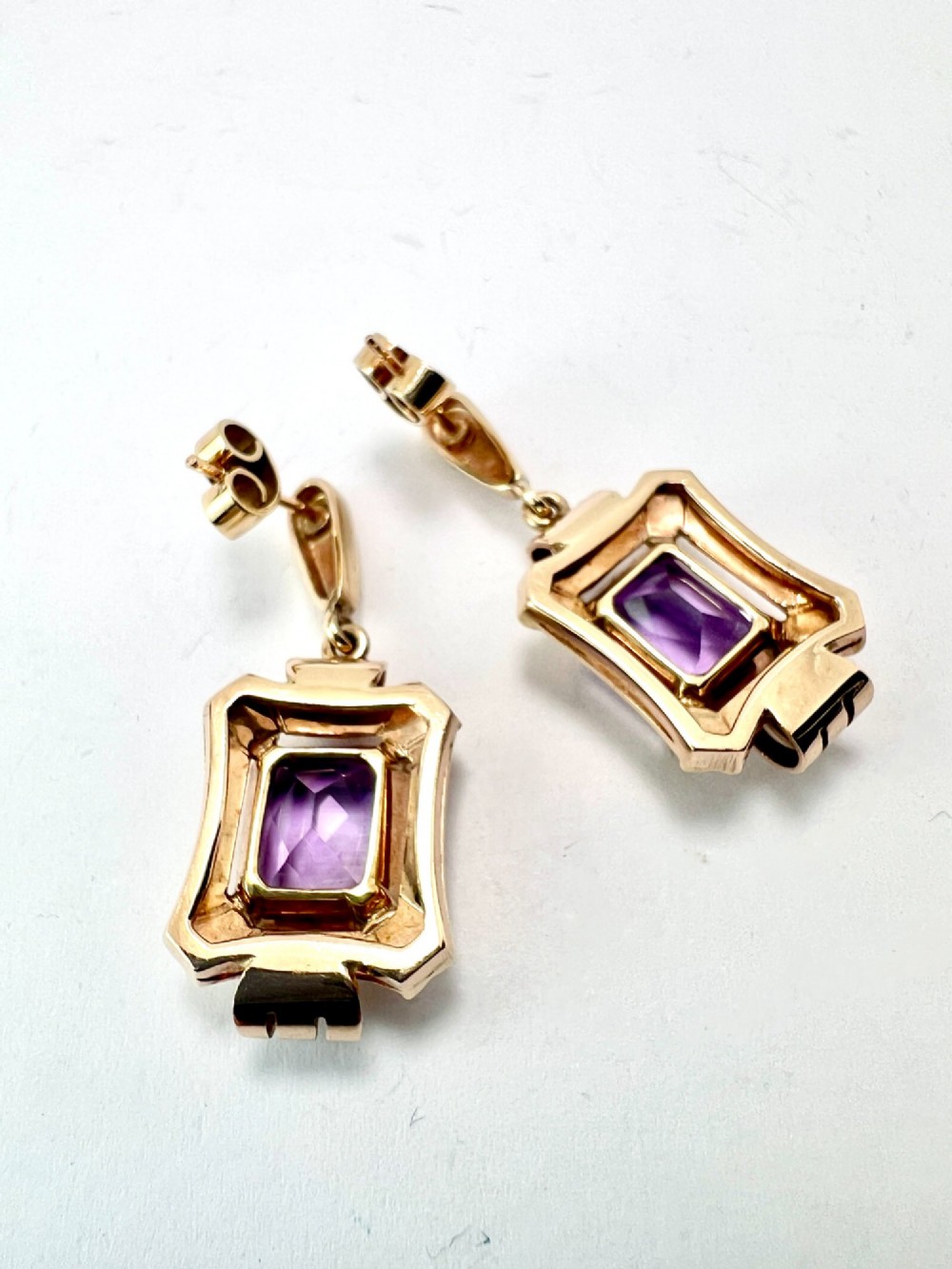 A pair of late Art Deco gold drop earrings featuring rectangular emerald-cut purple amethyst stones set within fluted geometric mounts. View IV