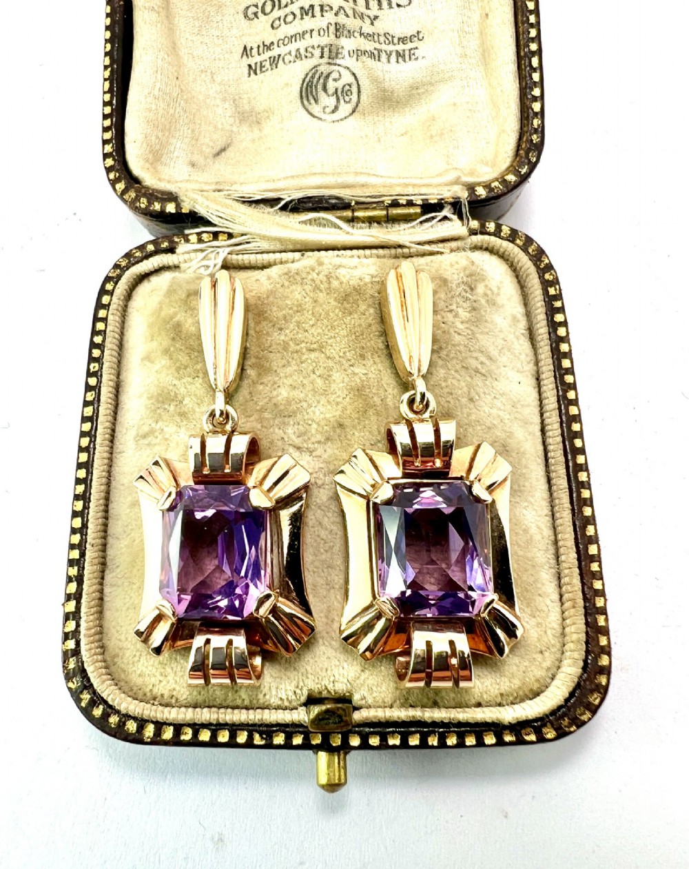 A pair of late Art Deco gold drop earrings featuring rectangular emerald-cut purple amethyst stones set within fluted geometric mounts. View VI
