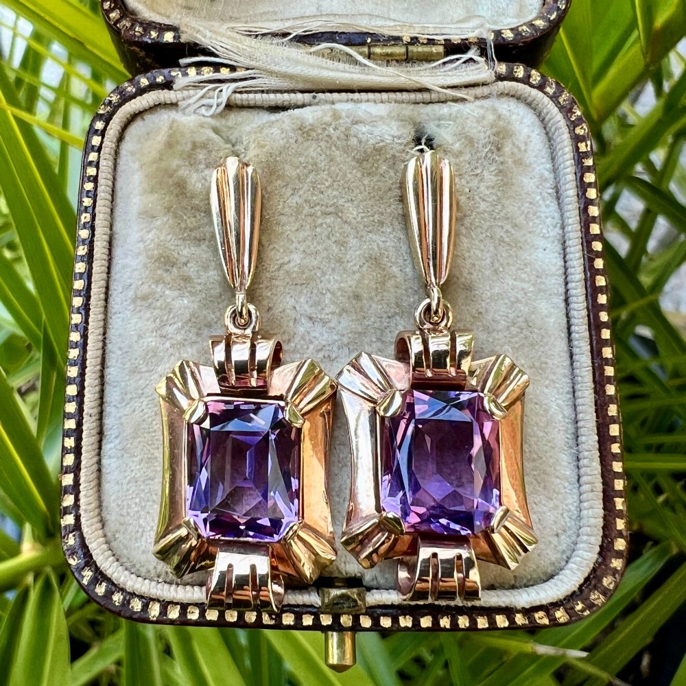 A pair of late Art Deco gold drop earrings featuring rectangular emerald-cut purple amethyst stones set within fluted geometric mounts. View VII