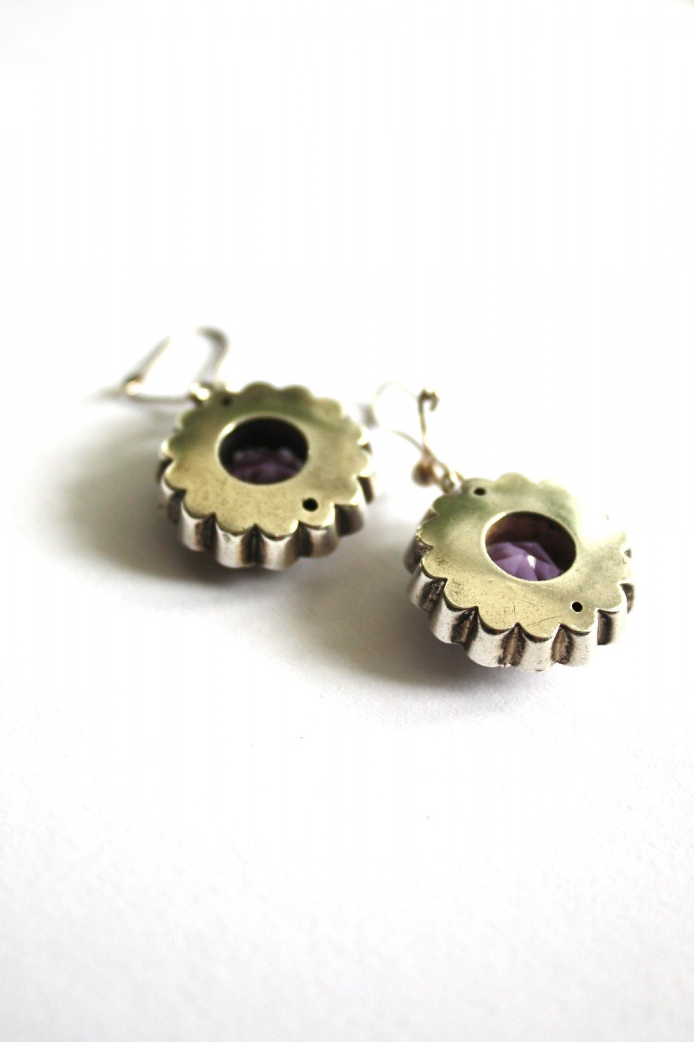 A Victorian silver jewellery set comprising a circular brooch and matching drop earrings, each featuring engraved detailing and a central faceted purple amethyst stone. View IV