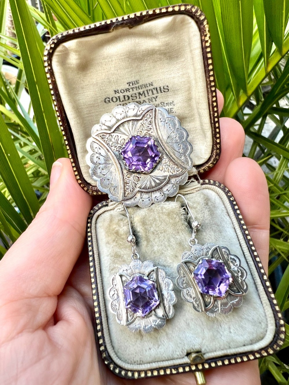 A Victorian silver jewellery set comprising a circular brooch and matching drop earrings, each featuring engraved detailing and a central faceted purple amethyst stone. View VIII