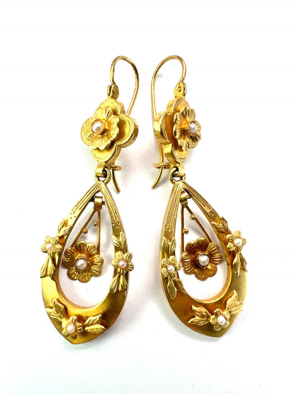 A pair of late Victorian yellow gold drop earrings featuring floral detailing and central pearl settings. View V
