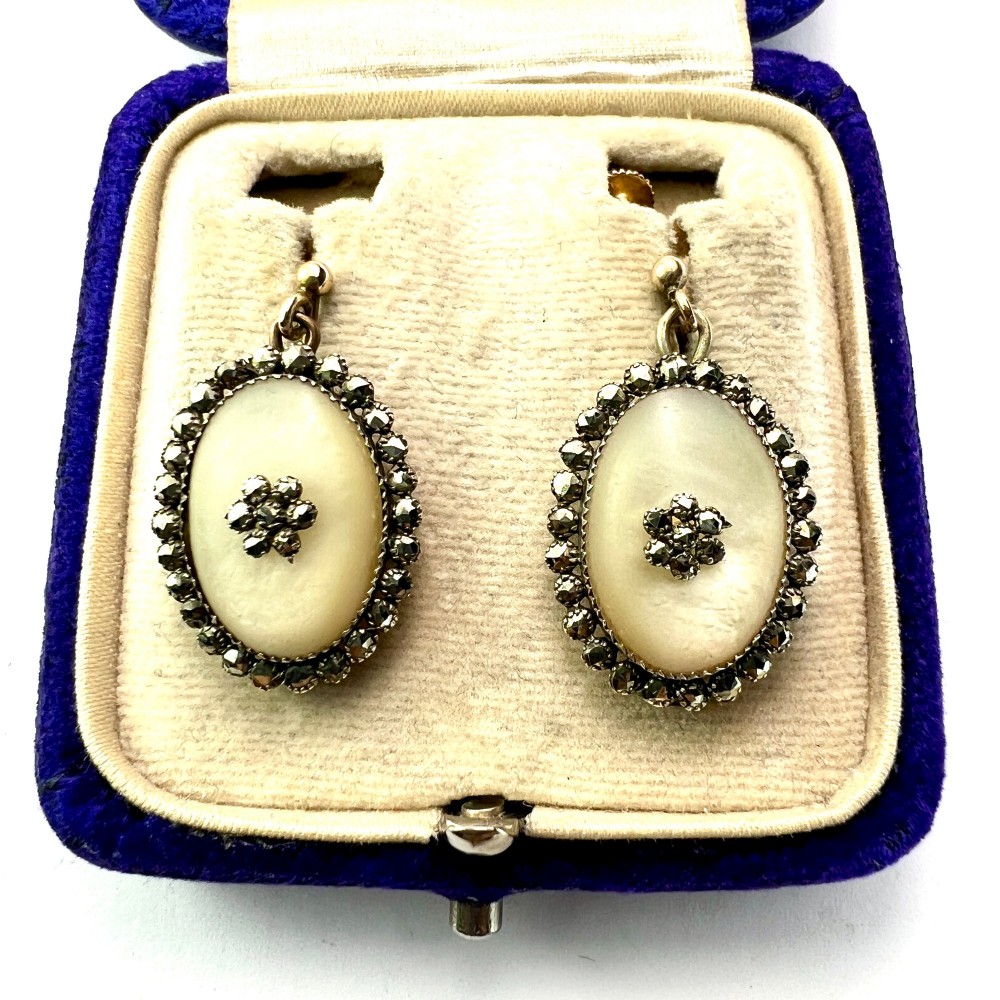 A pair of oval Georgian drop earrings featuring mother of pearl cabochons framed by faceted marcasite stones with a central marcasite floral cluster. View II