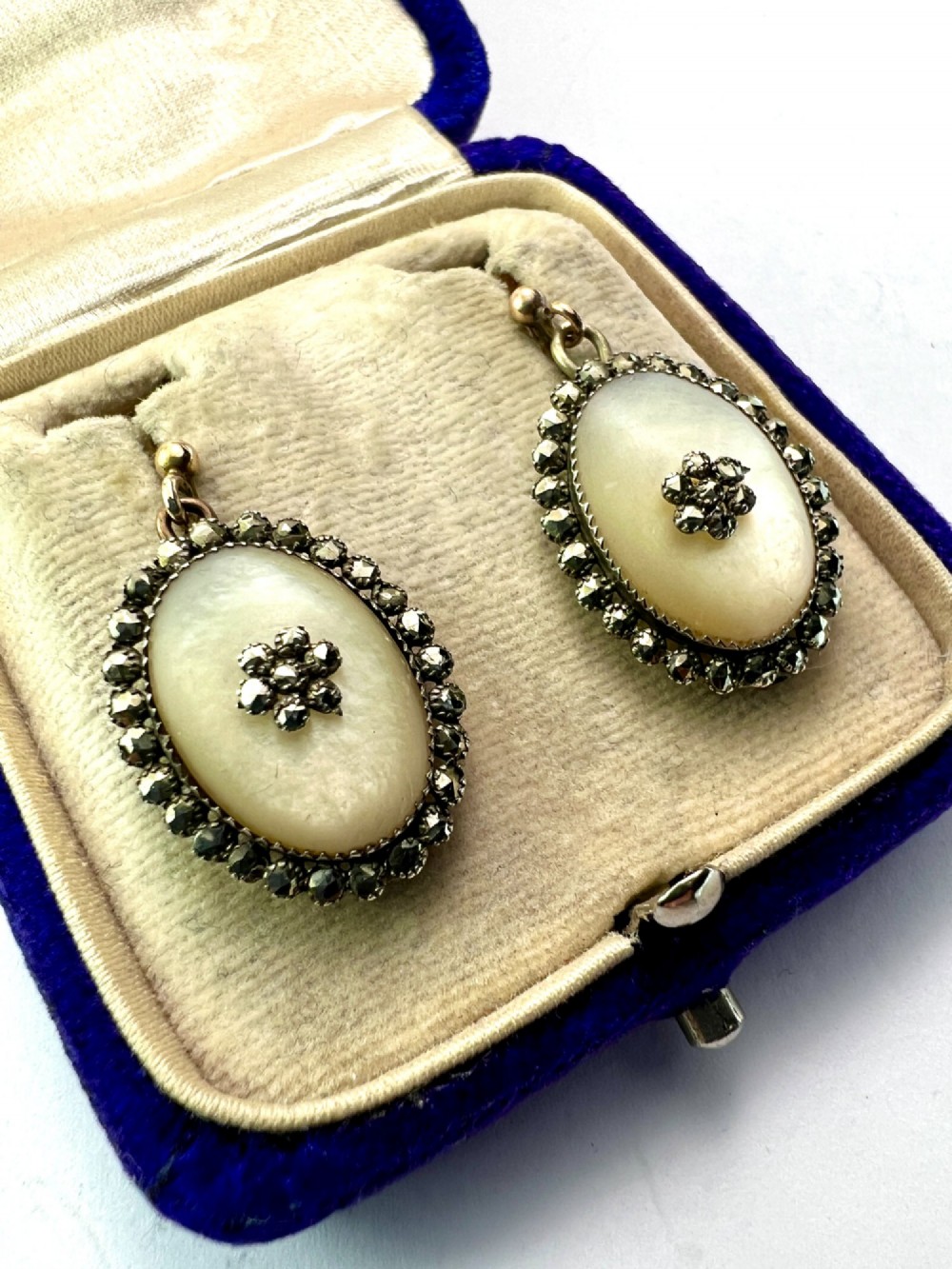 A pair of oval Georgian drop earrings featuring mother of pearl cabochons framed by faceted marcasite stones with a central marcasite floral cluster. View III