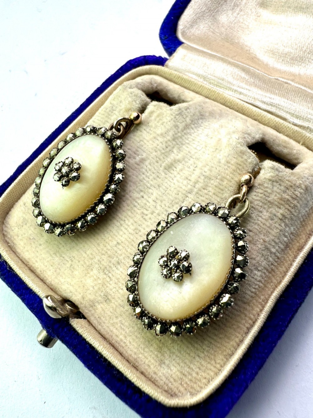 A pair of oval Georgian drop earrings featuring mother of pearl cabochons framed by faceted marcasite stones with a central marcasite floral cluster. View IV