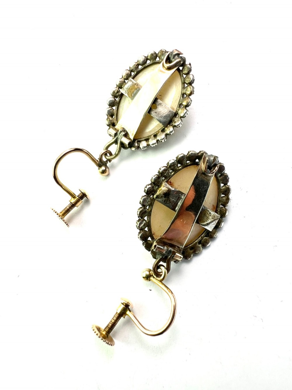 A pair of oval Georgian drop earrings featuring mother of pearl cabochons framed by faceted marcasite stones with a central marcasite floral cluster. View V