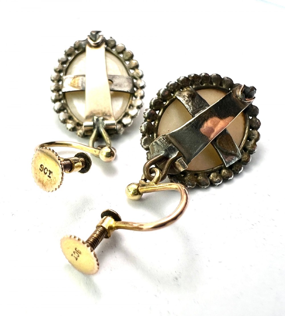 A pair of oval Georgian drop earrings featuring mother of pearl cabochons framed by faceted marcasite stones with a central marcasite floral cluster. View VI